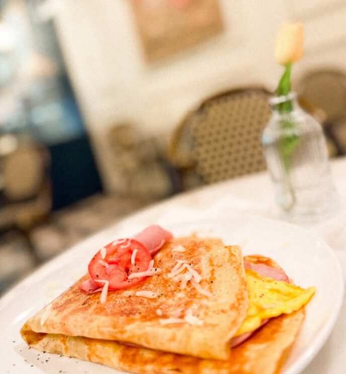 A savory crêpe with egg, ham and tomato on a white plate at Creperie Antoinette