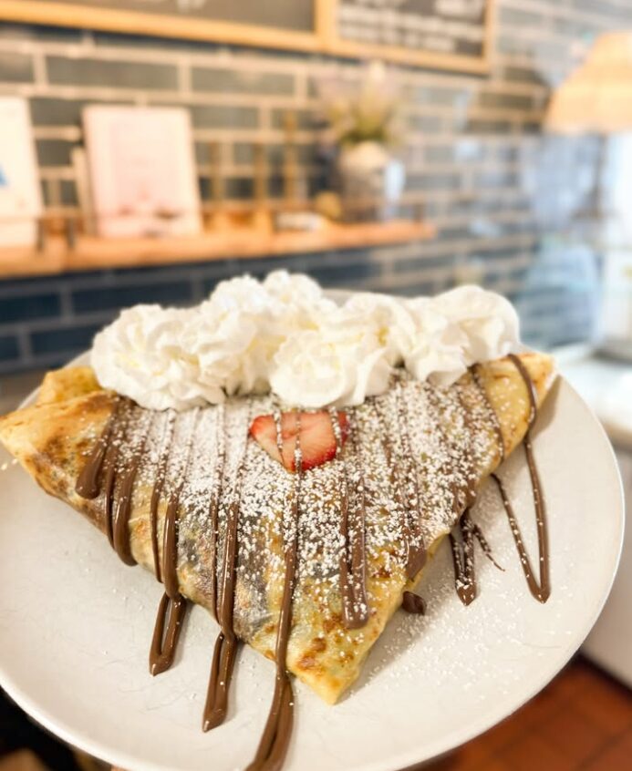 A Nutella crêpe with fresh strawberries, whipped cream and powdered sugar