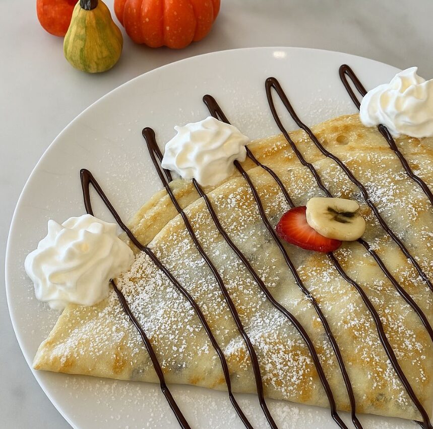 A banana crêpe with chocolate drizzle and whipped cream